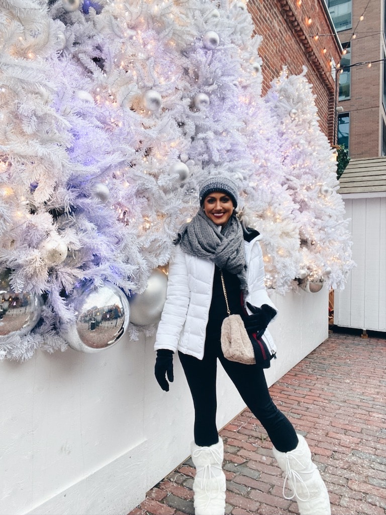 Girl in winter gear standing beside Christmas garland