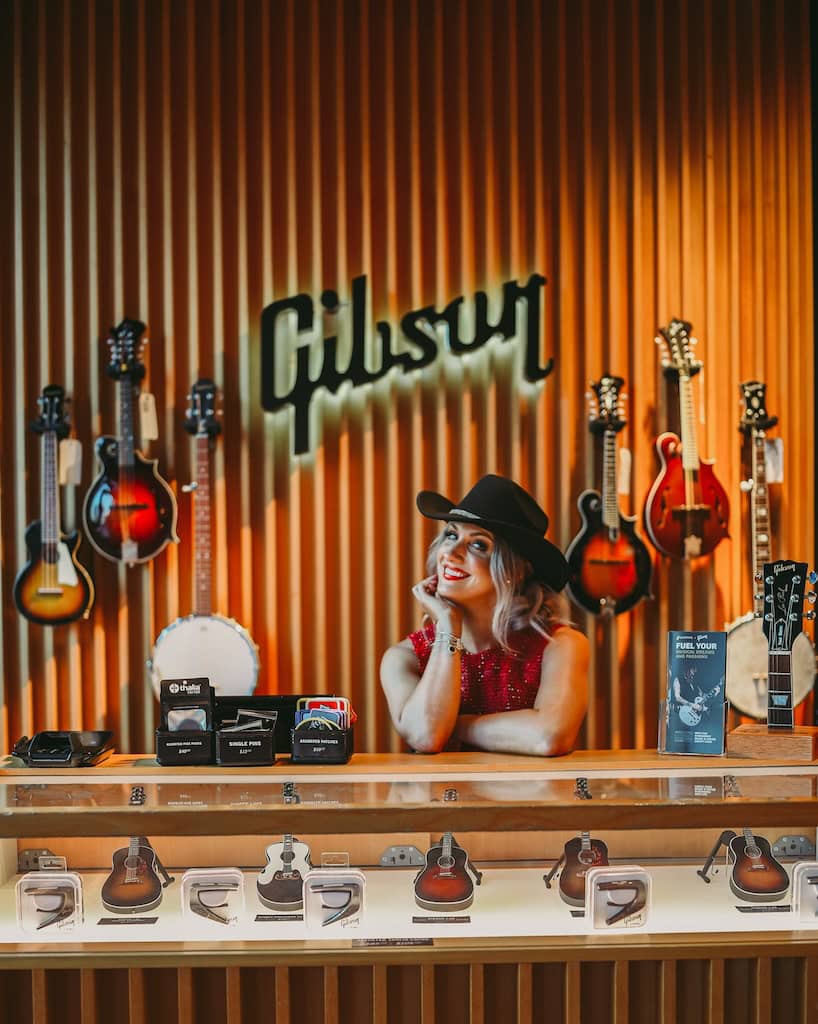 Girl posing in front of the Gibson sign during a musician photoshoot at Gibson Garage Nashville