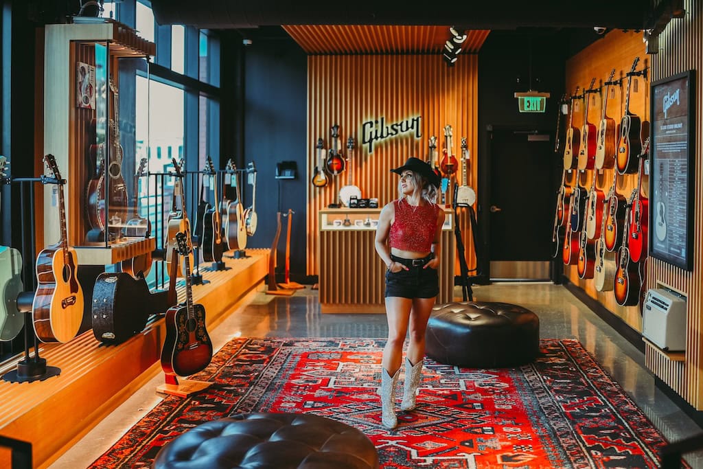 Girl posing in front of the Gibson sign during a musician photoshoot at Gibson Garage Nashville