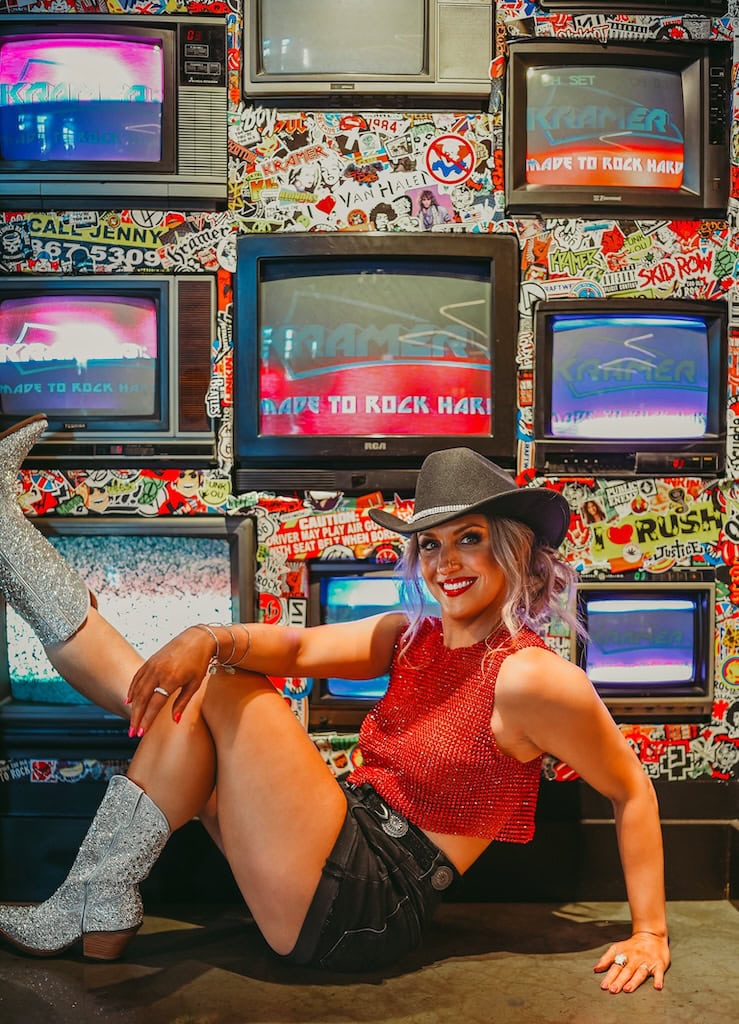 Girl posing in front of TVs at Gibson Garage Nashville