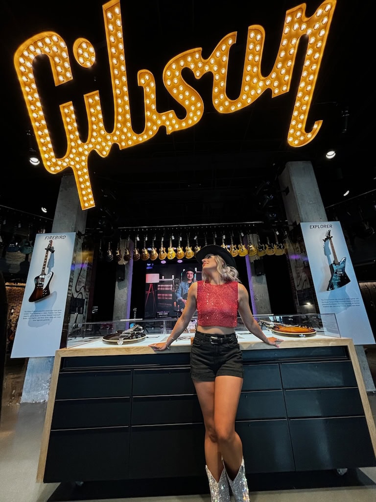 Girl posing under the Gibson sign at Gibson Guitar Nashville during a musician photoshoot