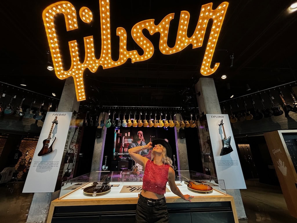 Girl posing under the Gibson sign at Gibson Guitar Nashville during a musician photoshoot