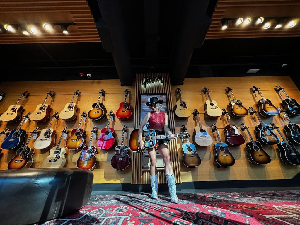 Girl holding an acoustic guitar during a musician photoshoot at Gibson Garage Nashville