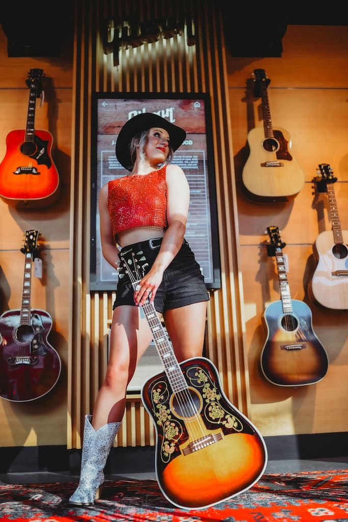 Girl holding an acoustic guitar during a musician photoshoot at Gibson Garage Nashville