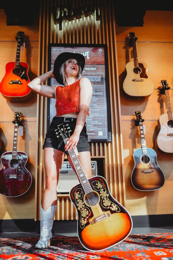 Girl holding an acoustic guitar during a musician photoshoot at Gibson Garage Nashville