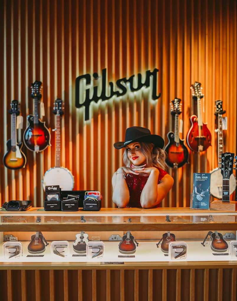 Girl posing in front of the Gibson sign during a musician photoshoot at Gibson Garage Nashville