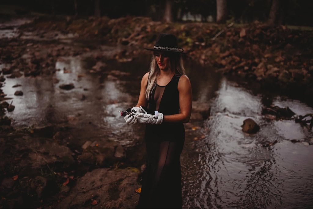 Girl standing in water getting ready to ignite a colored smoke bomb.