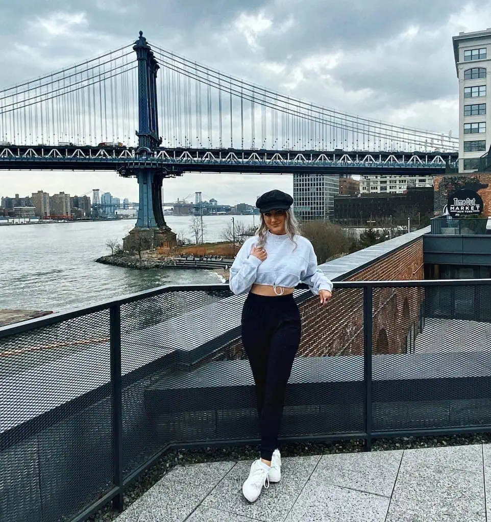 Girl standing in NYC with the Brooklyn Bridge in the background.