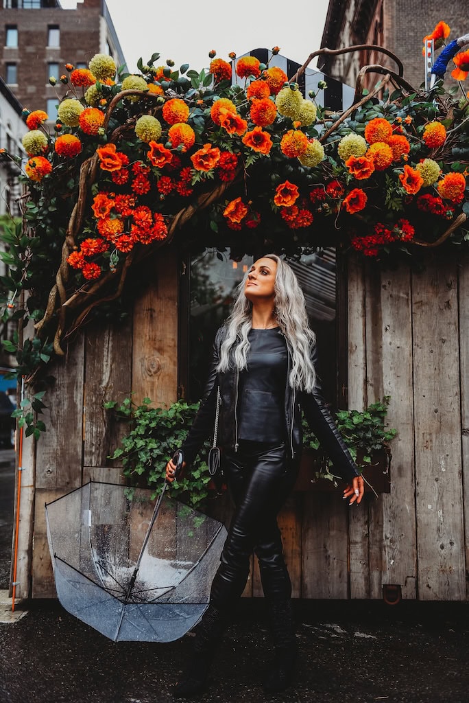 Girl posing in New York City by some flowers.