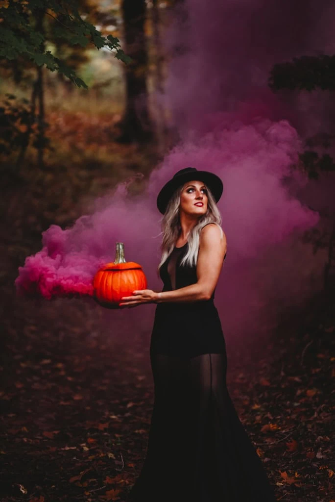 Girl using smoke bombs and a pumpikin in photos for a Halloween photoshoot